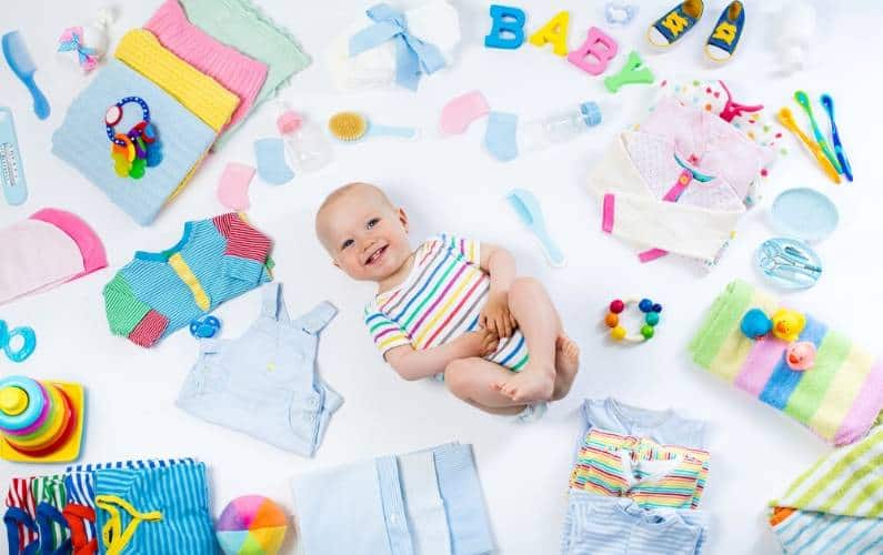 baby laying down surrounded by baby items