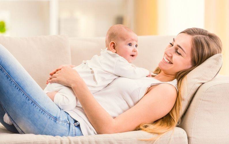 new mom laying down on couch while holding baby