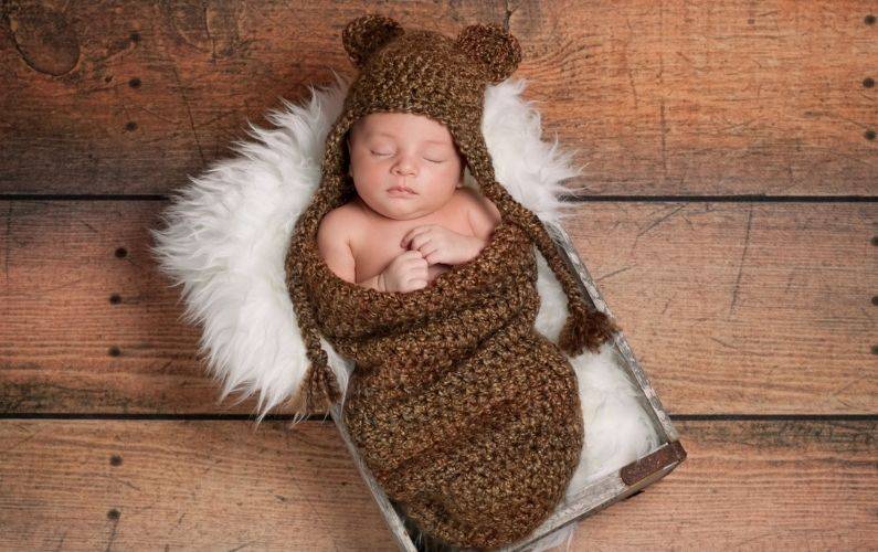 baby boy wrapped up in a brown knitted fabric