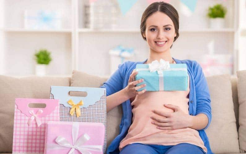 pregnant woman holding belly while sitting with gifts