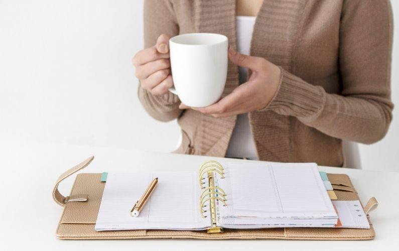 women holding coffee using a planner