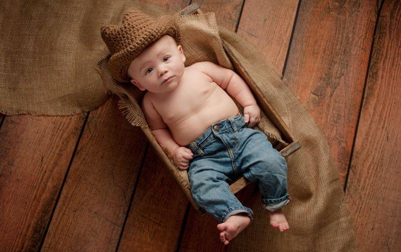 baby boy dresses in blue jean and a brown cowboy hat