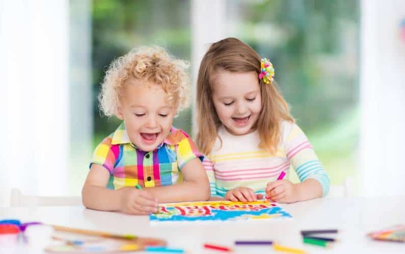 2 toddler girls smiling while doing a coloring activity